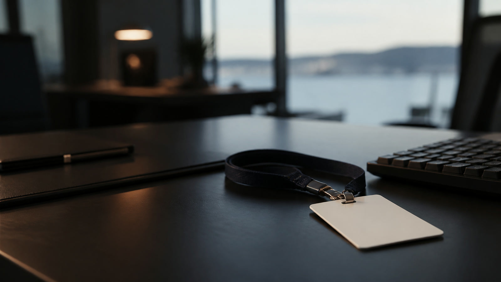 An employee badge on a lanyard resting on a desk beside a keyboard