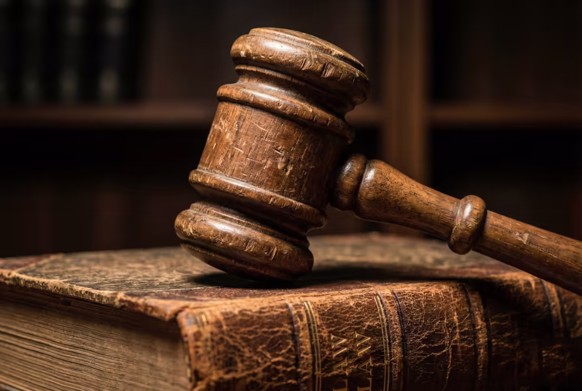 Wooden gavel resting on an old leather-bound law book